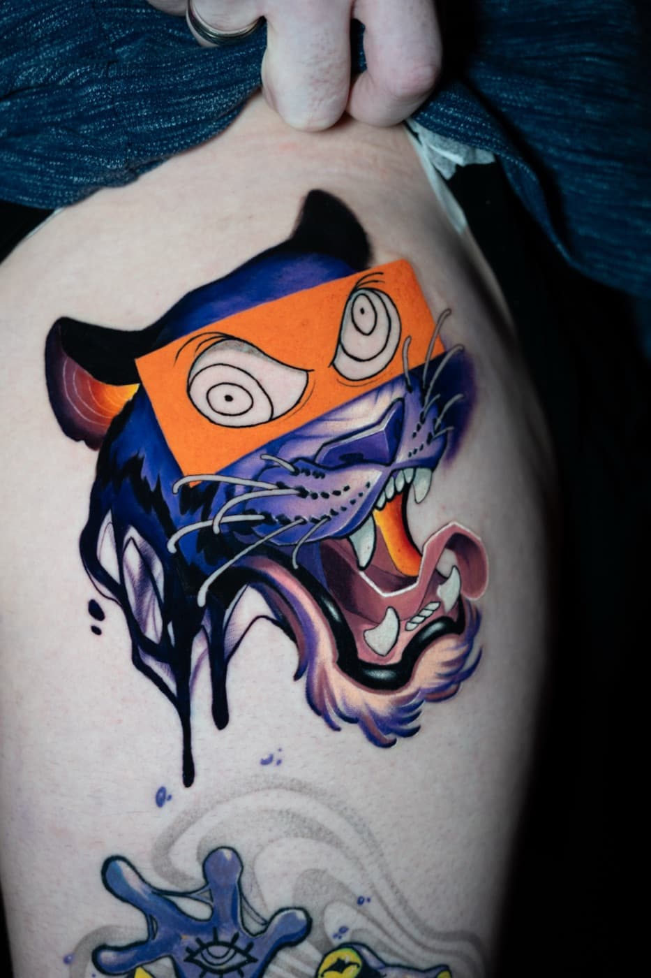 Colour tattoo of a tiger with a graphic eye-mask design, orange and purple